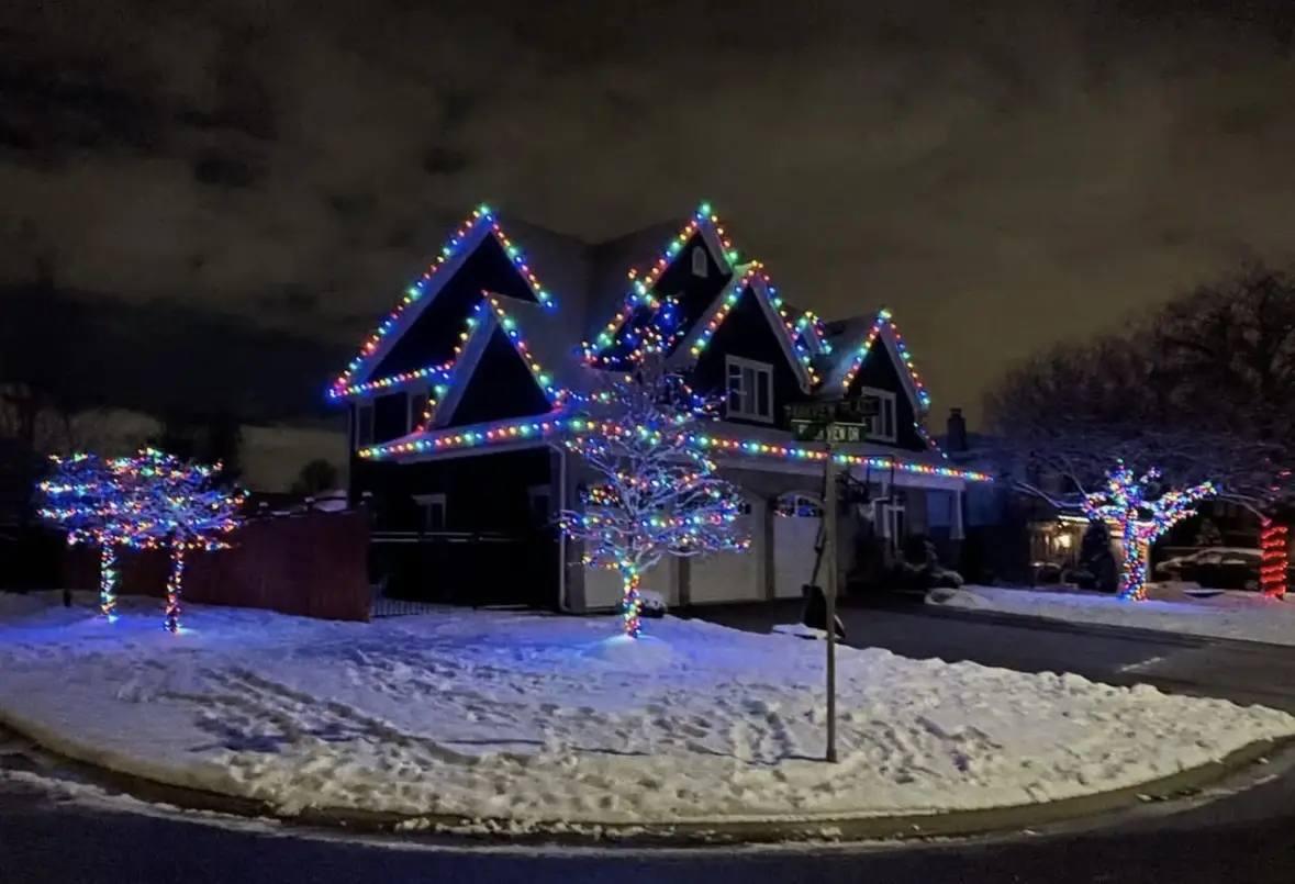 Colourful Christmas lighting installation on a snow-covered home