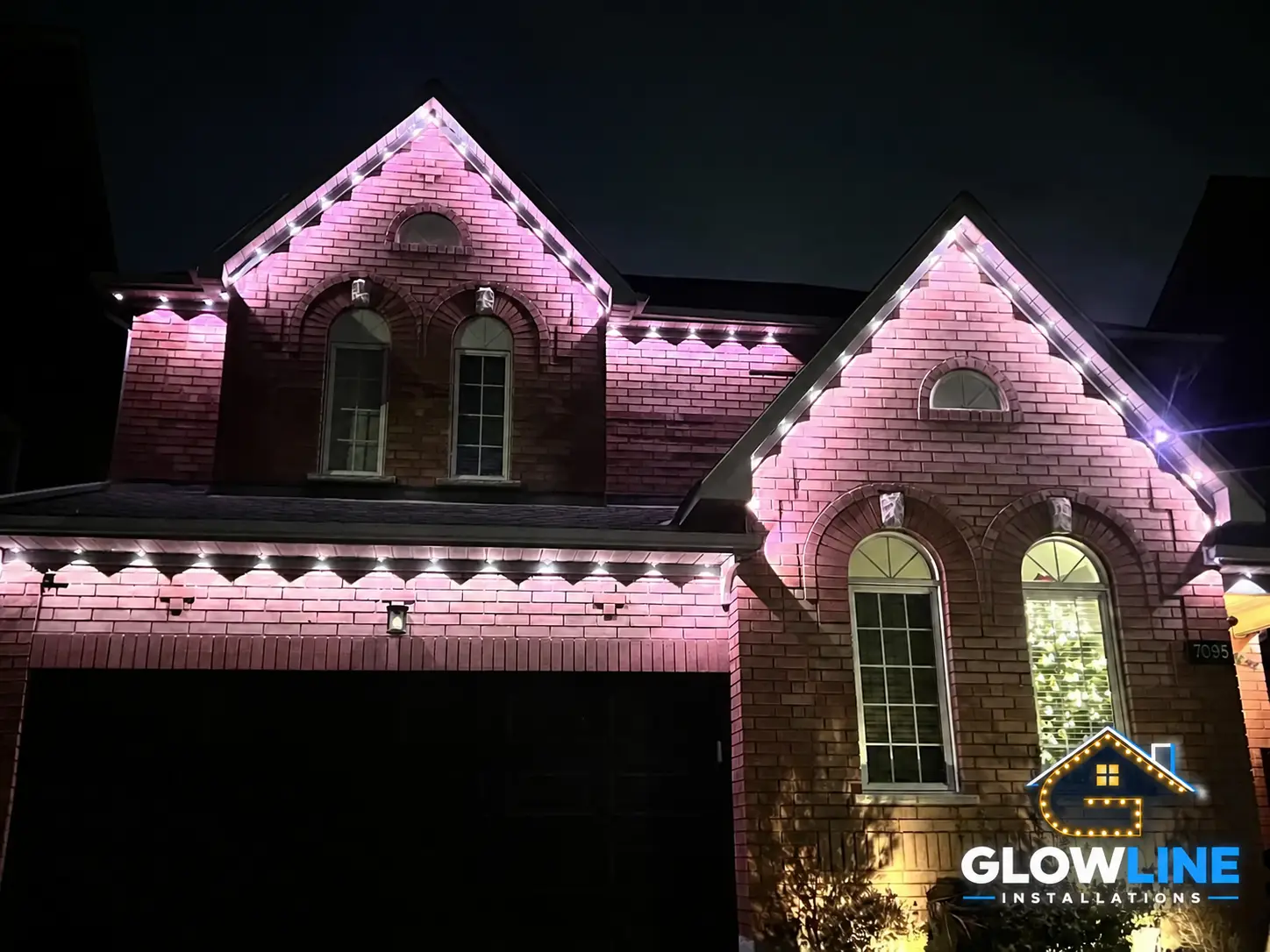 Stone home with pink permanent roofline lights